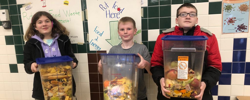 Kids holding collected food waste in bins