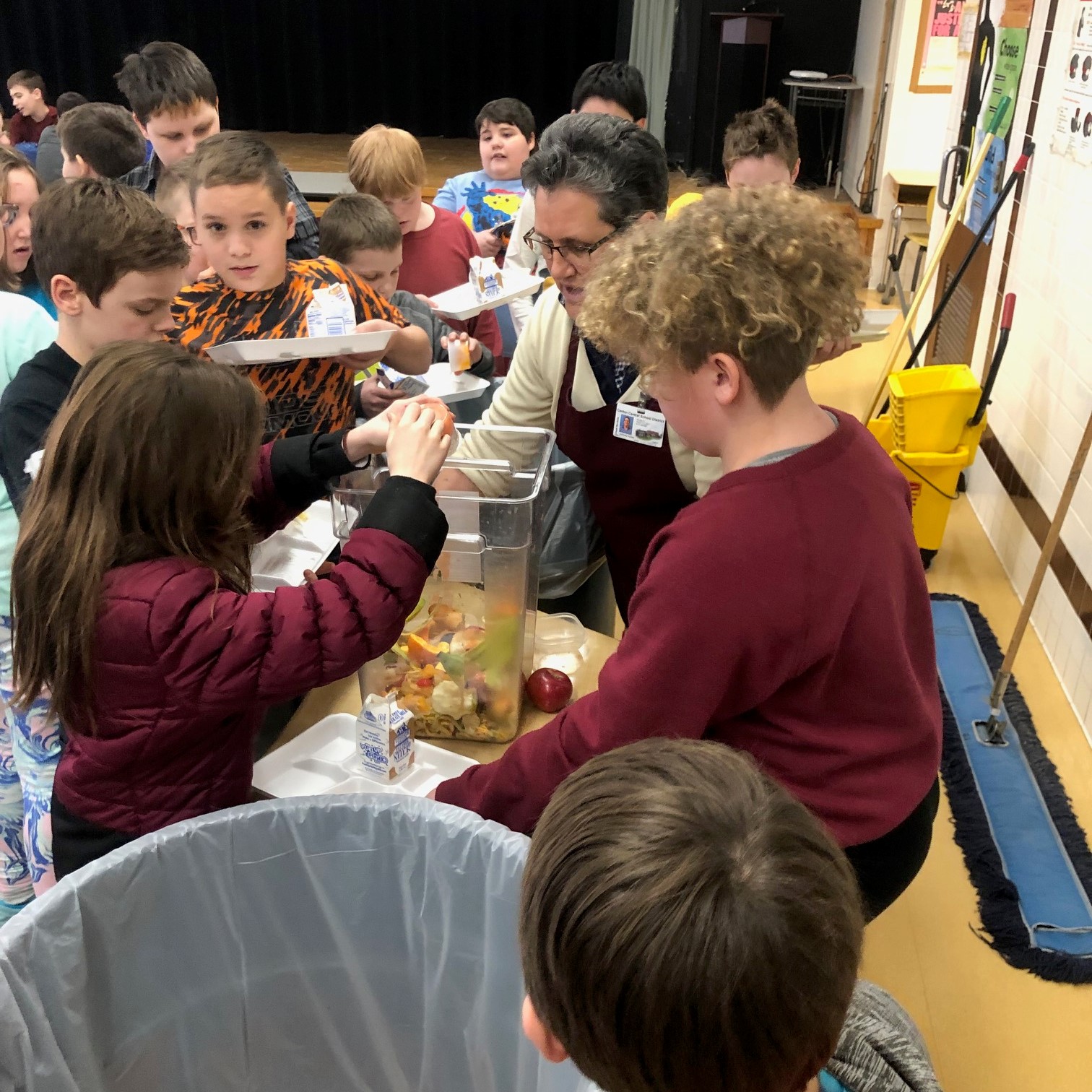 Middle school students sorting their food waste with the help of a CCE employee